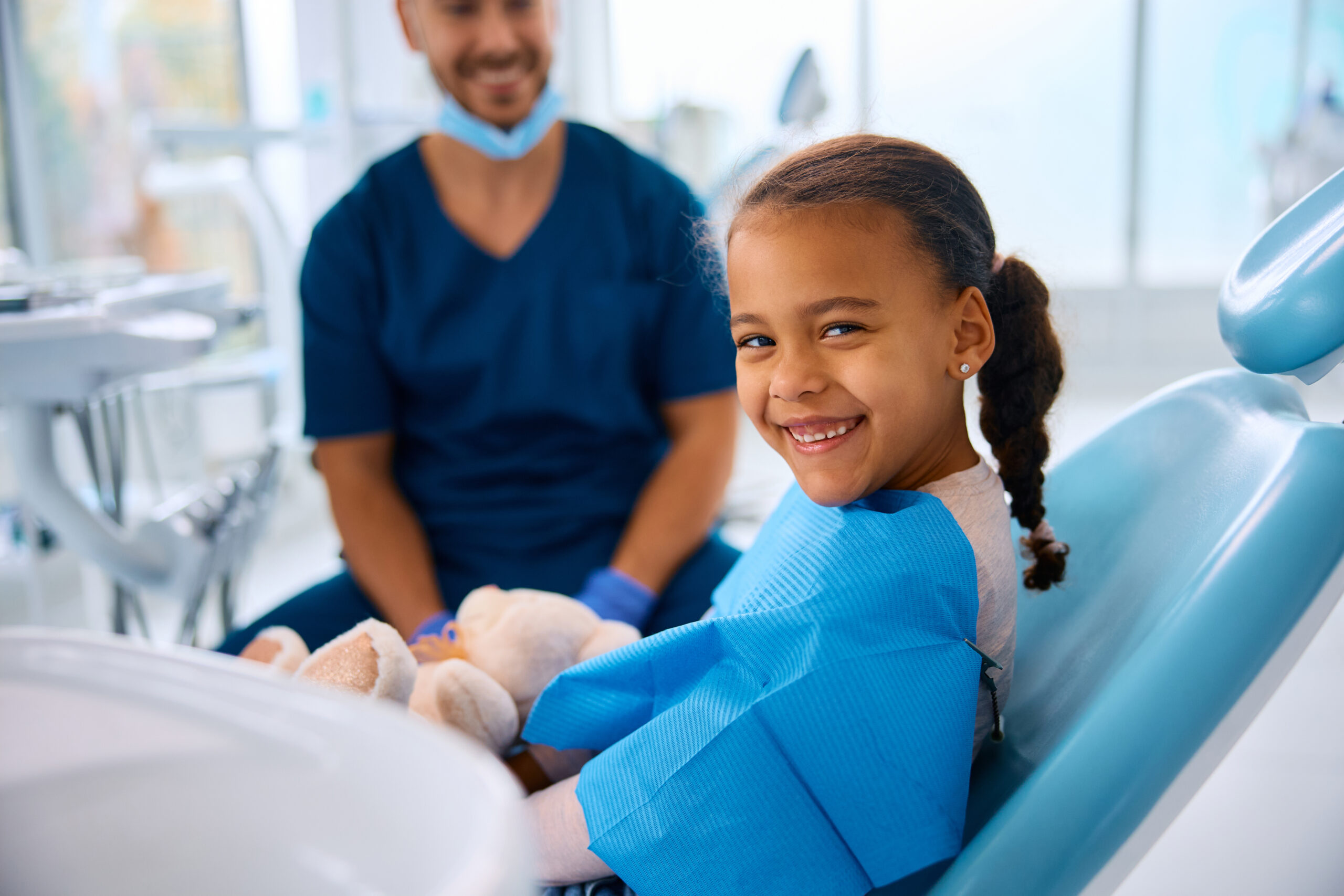 Smiling girl in a dental chair at a pediatric dentist appointment.